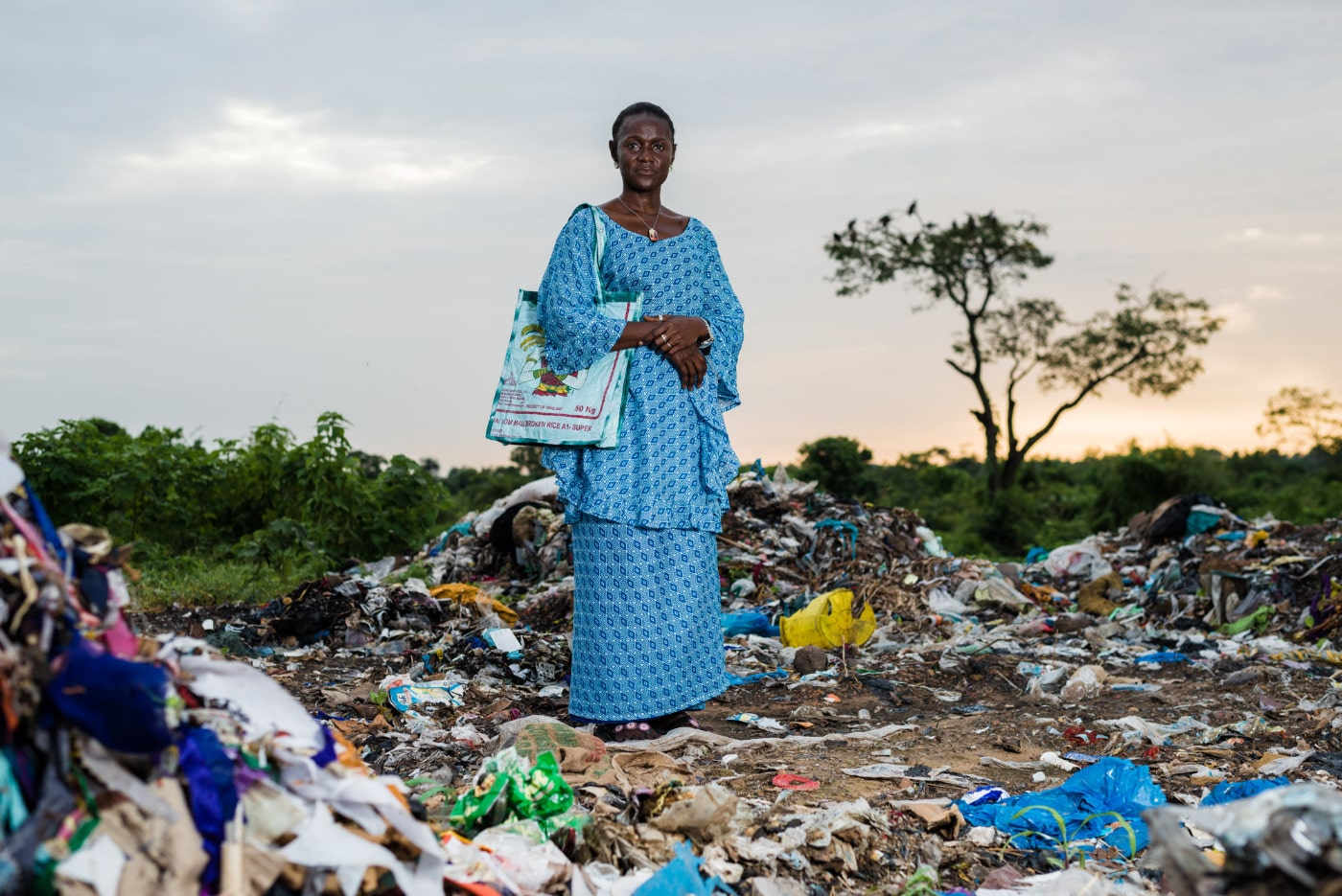 Image illustrant Climate Heroes. une femme se tient au milieu d'une décharge à ciel ouvert.